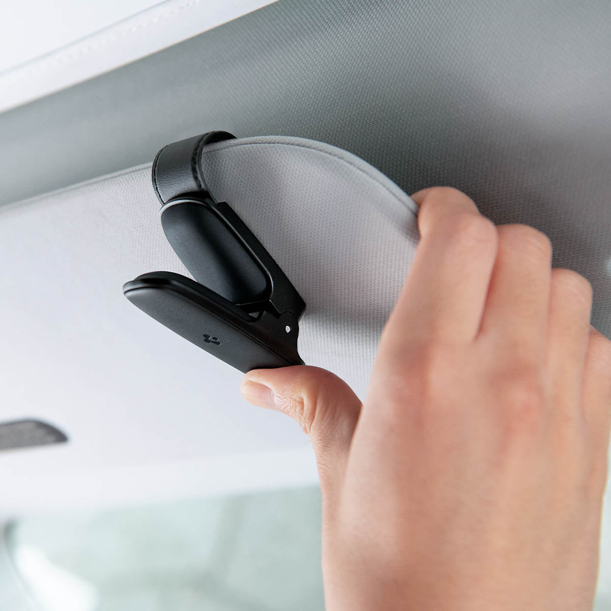 ACP08824 - Visor Sunglass Holder SH100 in Black showing a hand opening the holder
