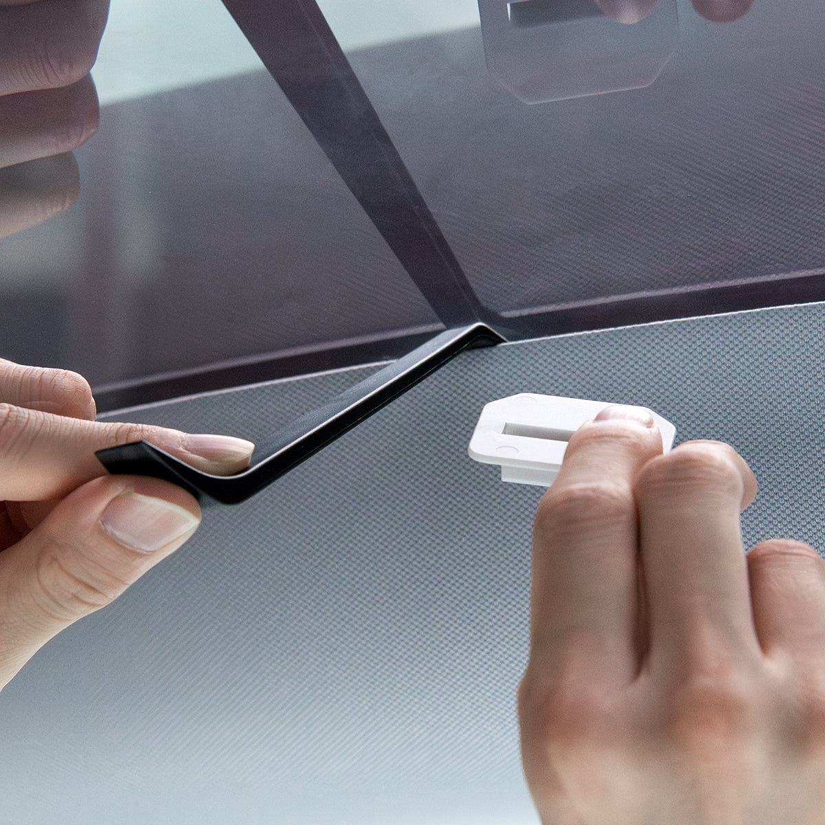 ACP09568 - Model Y (2025) CryoShade Sunroof in Gray showing a person holding a prying tool on other hand and clip on the other